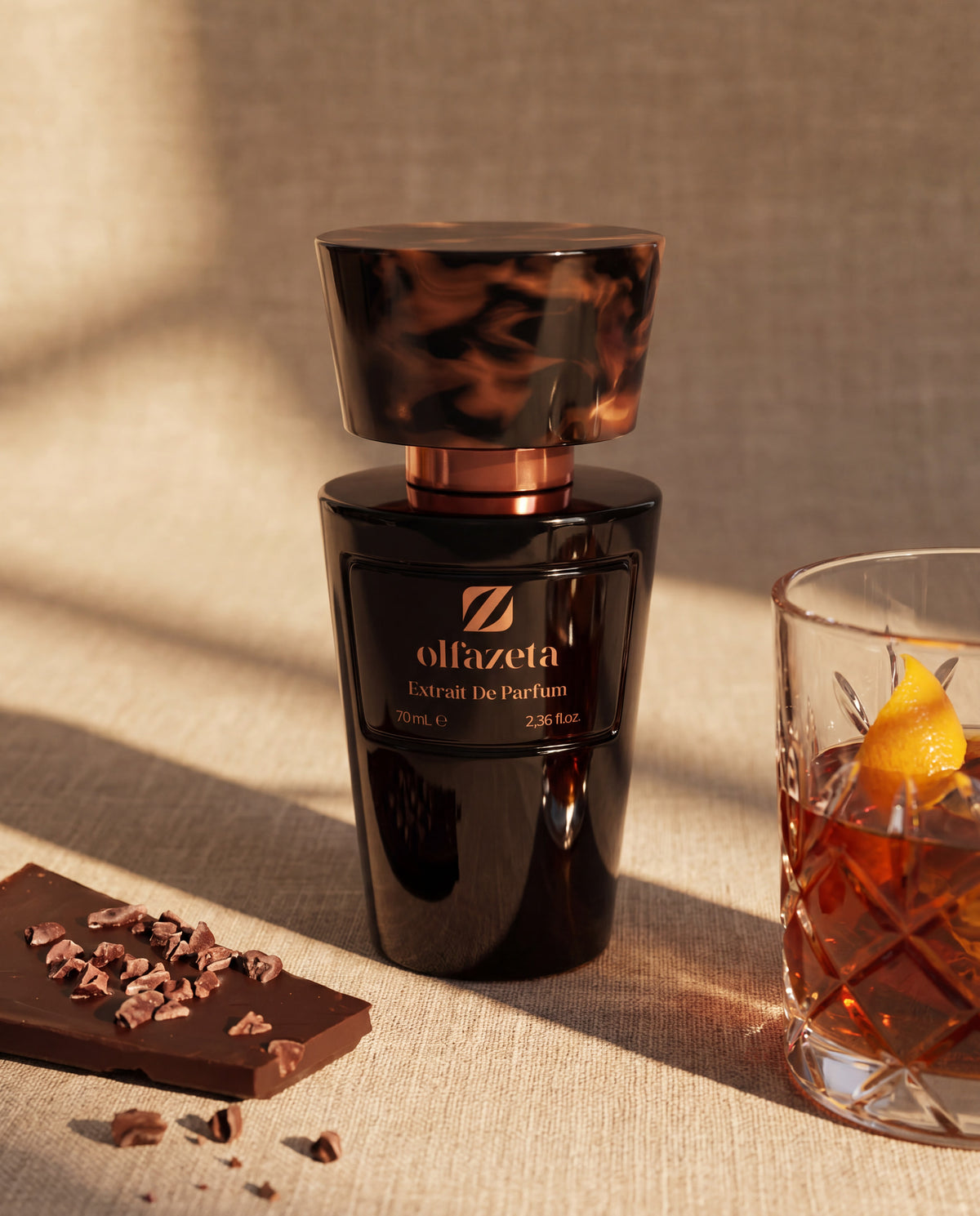 Fekete flakon Olfazeta by Chogan Millésime N°30 lenvásznon, étcsokoládé és egy pohár whisky narancshéjjal